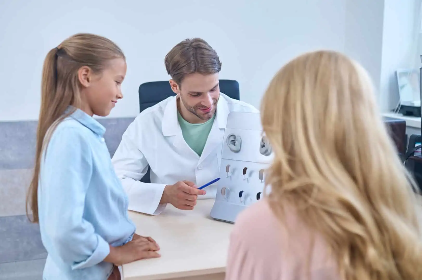 An Audiologist showing hearing aids for a child accompanied by the parent.