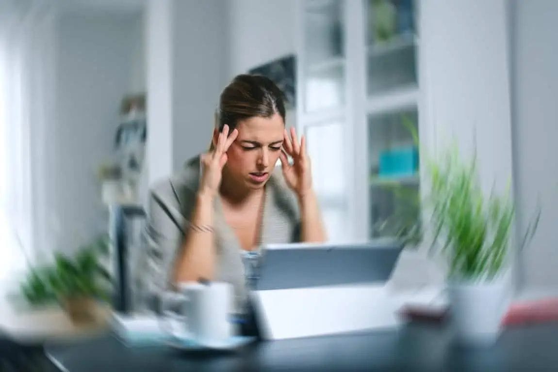 An image of a lady feeling vertigo while working on a computer.