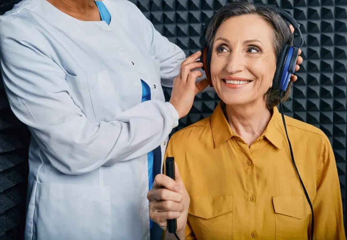 A lady with hearing loss being having her hearing test with an audiologist
