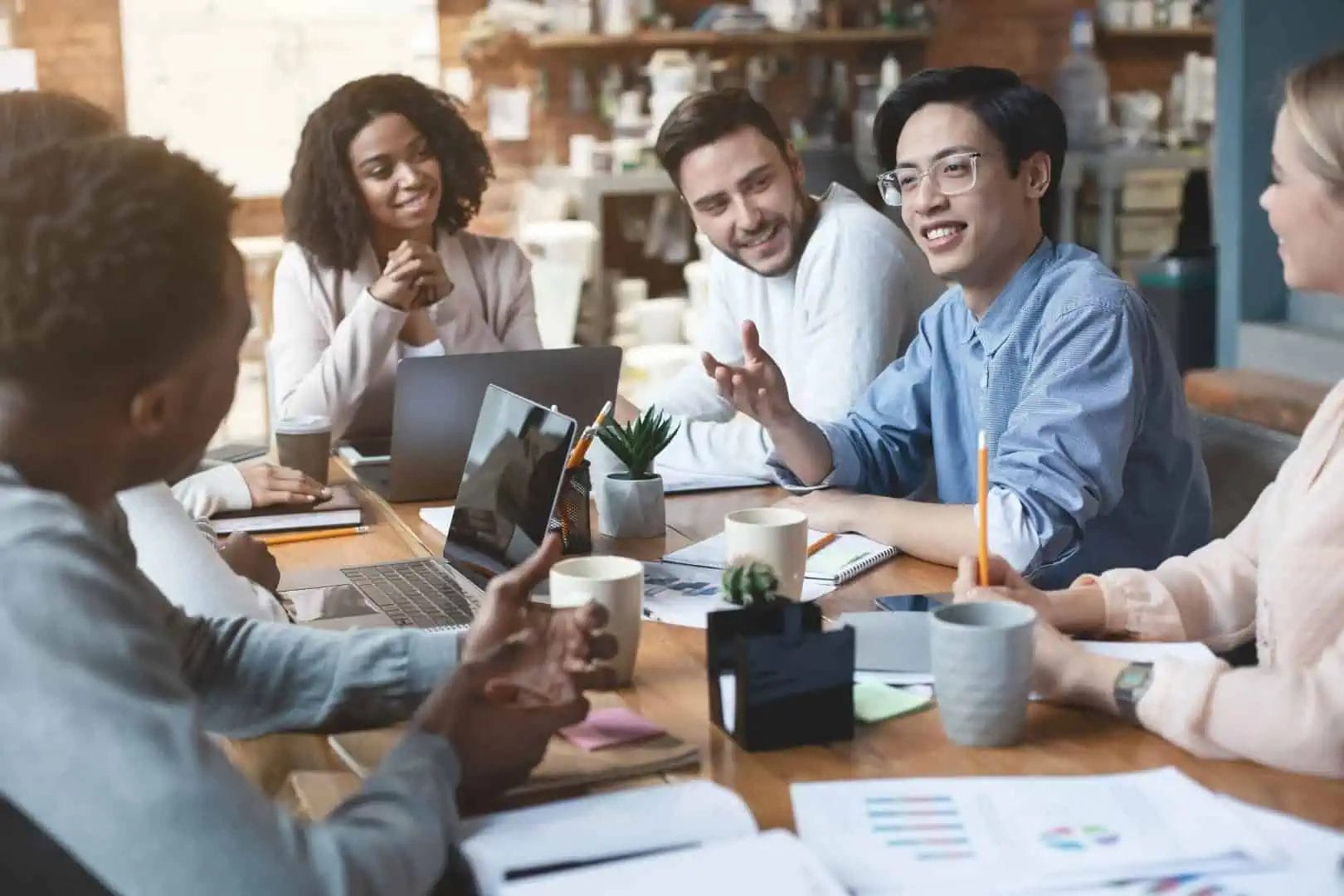 A group of people discussing in a meeting while a person with hearing loss using hearing aid to hear better